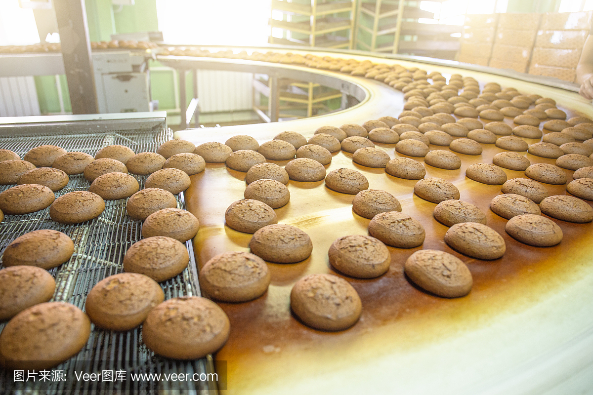 烘培生产线或用新鲜的甜饼放在传送带上。设备机械在糖果工厂车间,工业食品生产